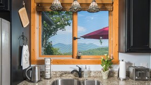 A kitchen with a granite countertop, stainless steel sink, a coffee pot, a toaster, and a window with a view of mountains. - 1st in Sugar/View/EV Charge/Hot Tub/Sauna/Pet Friendly/Sleeps 12/Two Master Bdrs (Sugar Mountain)