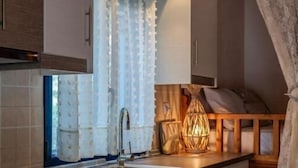 A modern kitchen with a built-in oven, a stainless steel sink, and wooden cabinets. - Irene's Cottage Myrtonas (Karpathos)