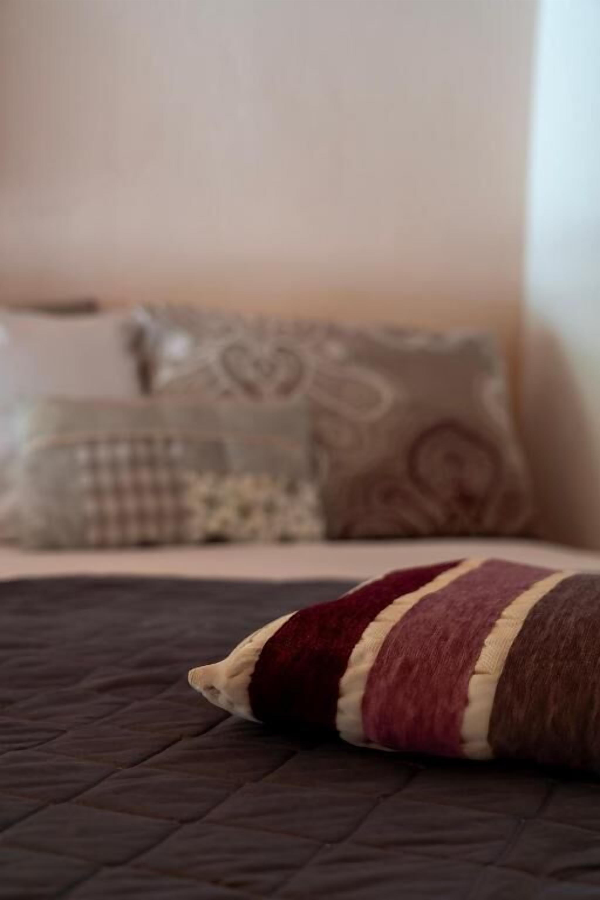 Una cama con colcha oscura y almohada a rayas.