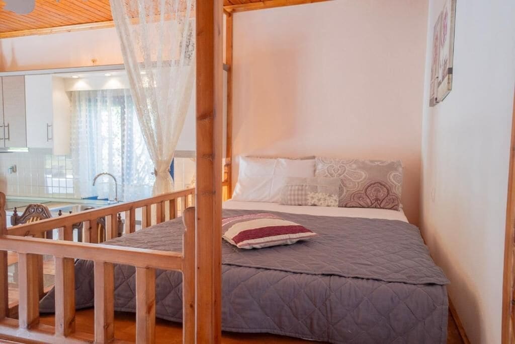 Une chambre à coucher avec un cadre de lit en bois, un baldaquin et une vue sur la cuisine et la salle de bain.
