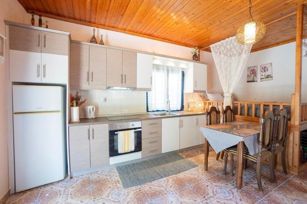 Una cocina funcional con comedor, techo de madera y piso de baldosas.