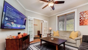 A living room with a TV, sofa, coffee table, and a ceiling fan. - Beautiful 3 Story Home in Best Tower Grove Location (St. Louis)