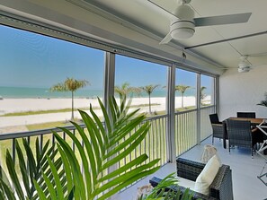 Ein Balkon mit Blick auf den Strand, Korbmöbel und einem Deckenventilator.