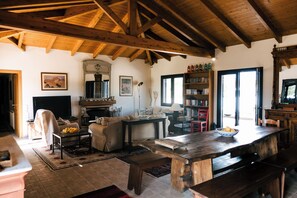 Un intérieur rustique avec un plafond en bois, une cheminée, une bibliothÚque et un coin repas.