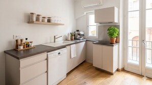 Ett modernt kök med diskmaskin, kaffemaskin och en krukväxt.