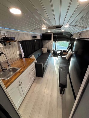 A compact RV interior with a kitchenette, a seating area, and a small dining space. - Perfect 2-bedroom barn with AC in beautiful Taylor (Taylor)