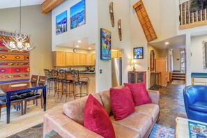 A spacious living area with a leather sofa, a dining table, and a kitchen in the background. - Ski-in/out|Free Shuttle|Private Hot Tub|Garage (Breckenridge)