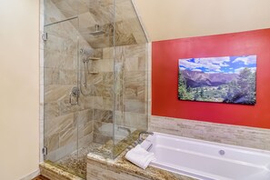A bathroom with a glass-enclosed shower, a white bathtub, and a red accent wall. - Ski-in/out|Free Shuttle|Private Hot Tub|Garage (Breckenridge)