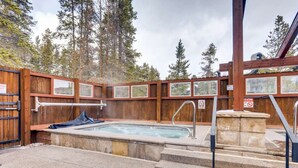 Un área de jacuzzi con terraza de madera, escalones de piedra y vista a árboles.