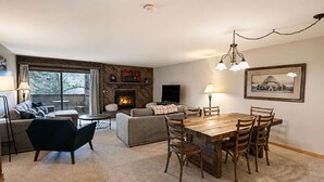 Una sala de estar con chimenea, sofá, mesa de comedor y sillas.