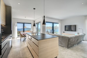 A modern kitchen with a dining area, a sofa, and a TV. - Luxury apartment with stunning views and pool (Seget Vranjica)