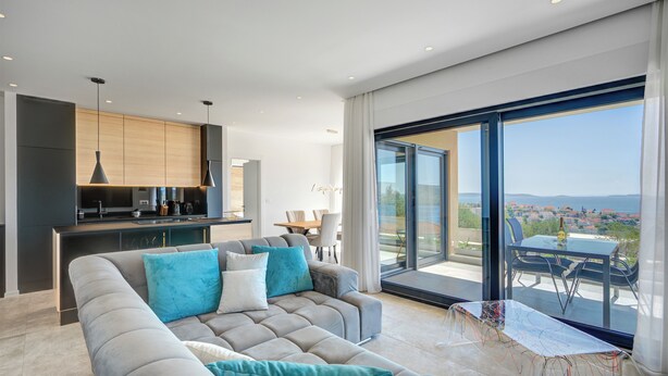 A modern living room with a sofa, a dining table, and a kitchen area. - Luxury apartment with stunning views and pool (Seget Vranjica)