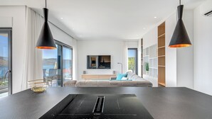 A modern kitchen with a Bosch induction cooktop, a dining table, and a sofa in the background. - Luxury apartment with stunning views and pool (Seget Vranjica)