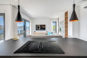 A modern kitchen with a Bosch induction cooktop, a dining table, and a sofa in the background. - Luxury apartment with stunning views and pool (Seget Vranjica)