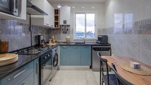 Une cuisine moderne équipée d’une cuisinière, d’un four et d’un lave-vaisselle, une fenêtre offrant une belle vue et un coin repas avec une table et des chaises.