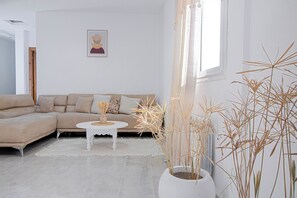 A living room with a beige sofa, a white coffee table, and a potted plant. - Sandra 7  (Sidi Bou Said)