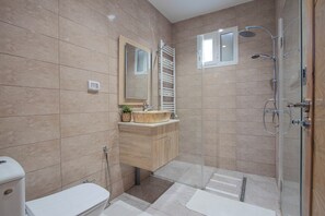 A modern bathroom with a toilet, sink, mirror, towel rack, shower, and glass-enclosed shower area. - Sandra 7  (Sidi Bou Said)