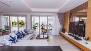 A modern living room with a sofa, coffee table, TV, and a balcony with outdoor furniture. - ANGSANALUXUREAPR (Thalang)