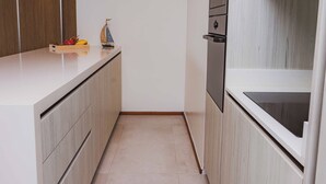 A modern kitchen with a white countertop, wooden cabinets, and a built-in oven. - ANGSANALUXUREAPR (Thalang)