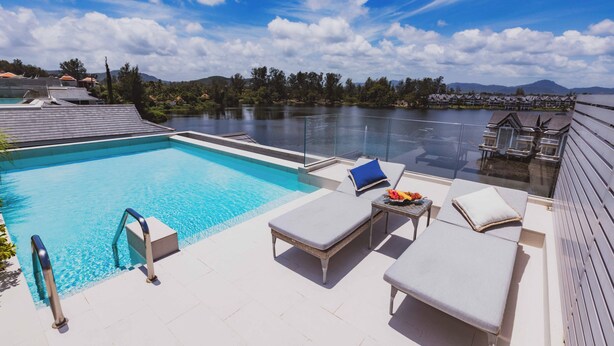 A pool area with lounge chairs, a table, and a view of a lake and mountains. - ANGSANALUXUREAPR (Thalang)