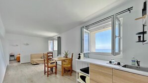 A modern kitchen with a large window, wooden chairs, a dining table, and a built-in sink. - Luxury villa - Les Galets (La Ciotat)