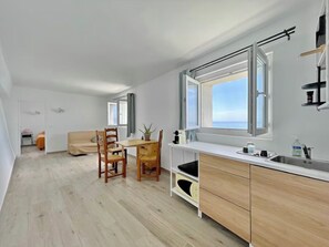 Eine moderne Küche mit einem großen Fenster, Holzstühlen, einem Esstisch und einer eingebauten Spüle.