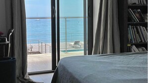 A room with a bed, a bookshelf, and a view of the sea through a large window. - Luxury villa - Les Galets (La Ciotat)