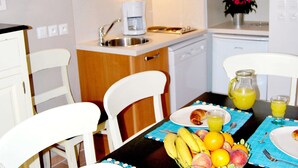 A kitchen with white cabinets, a coffee maker, a sink, and a dining table with chairs. - Cosy Village Studio Retreat in Barjac (Barjac)