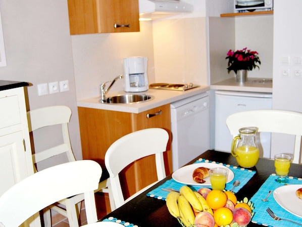 A kitchen with white cabinets, a coffee maker, a sink, and a dining table with chairs. - Cosy Village Studio Retreat in Barjac (Barjac)