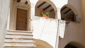Un edificio con puerta de madera, escaleras y ventanas de arco.