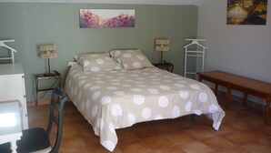 Ein Schlafzimmer mit einem Bett, einem Schreibtisch, einem Stuhl, einer Lampe und einer Bank.