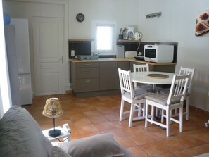 A compact kitchen with a dining area, a microwave, a kettle, and a clock on the wall. - Ground floor apartment facing the swimming pool, private property and parking on enclosed grounds (Salon-de-Provence)
