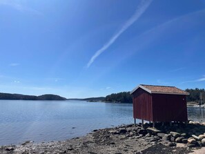 A red wooden structure by a calm lake with clear skies. - 4 Person Holiday Home in Uddevalla (Uddevalla)