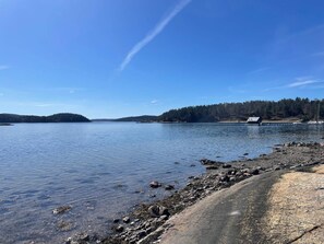 A calm lake with a rocky shoreline, a small dock, and a forested island in the distance. - 4 Person Holiday Home in Uddevalla (Uddevalla)