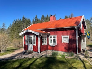 A red wooden house with a red tiled roof, white windows, and a Swedish flag. - 4 Person Holiday Home in Uddevalla (Uddevalla)