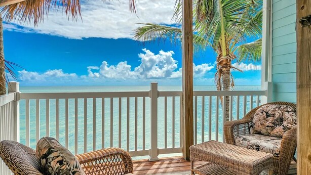 A covered outdoor area with wicker furniture, a wooden deck, and a view of the ocean. - Open Ocean, Sunrise and Moonrise. Tropical fish and Seabirds at your fingertips! (Duck Key)