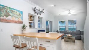 A kitchen with a wooden island, white cabinetry, and two bar stools. - Open Ocean, Sunrise and Moonrise. Tropical fish and Seabirds at your fingertips! (Duck Key)
