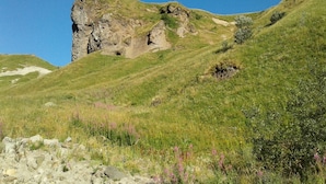 A rocky hill with a grassy slope and a clear blue sky. - Character apartment (Mont-Dore)