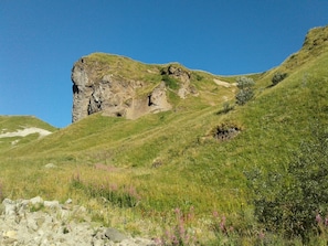 Ein felsiger Hügel mit einer grasbewachsenen Flanke und blauem Himmel.