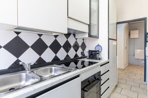 Eine kompakte Küche mit schwarz-weißer Küchenrückwand, Spüle aus Edelstahl und einem eingebauten Backofen.