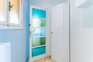 Una puerta blanca con paneles de vidrio esmerilado, un pomo de latón y un radiador blanco en la pared.