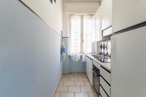 Una cocina estrecha con ventana, un lavamanos y una estufa.