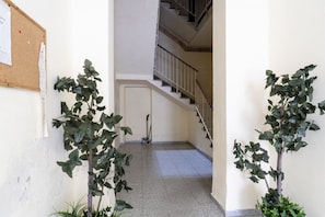 A hallway with a corkboard, potted plants, a staircase, and a mop leaning against the wall. - A bright apartment that sleeps up to four people, renovated with furnishings made by local artisans and located on the fourth floor (no elevator) in one of Livorno's most characteristic areas. The location is strategic: the sea and main attractions are w (Livorno)