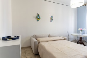 Un dormitorio con cama, escritorio y dos adornos en la pared.