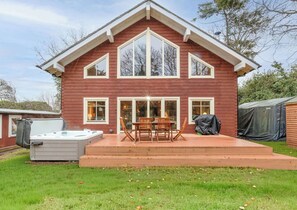 Ein zweistöckiges Haus mit überdachter Terrasse, Whirlpool und Grill.
