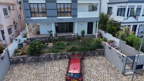 A modern two-story house with a paved driveway and a red car parked in the front. - J'Vais Residence Flic en Flac (Flic en Flac)