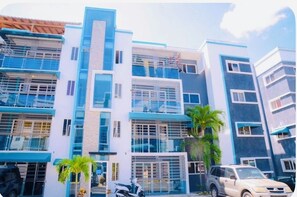 A multi-story building with a modern architectural design, featuring large windows and balconies. - “ Enjoy Your Coffee with Poolside Views at Harmony II – Balcony Bliss" (Santiago de los Caballeros)