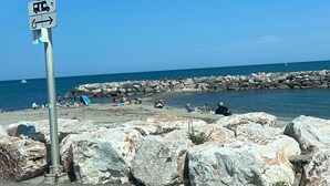 A coastal road with a no parking sign, a rocky breakwater, and a clear blue sky.
