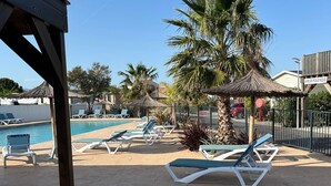 A poolside area with lounge chairs, a palm tree, and a wooden pergola.
