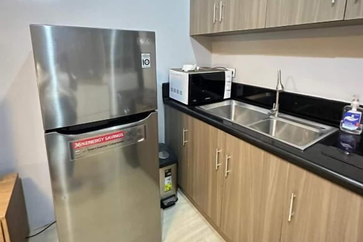 A kitchen with stainless steel appliances, wooden cabinets, and a black countertop.